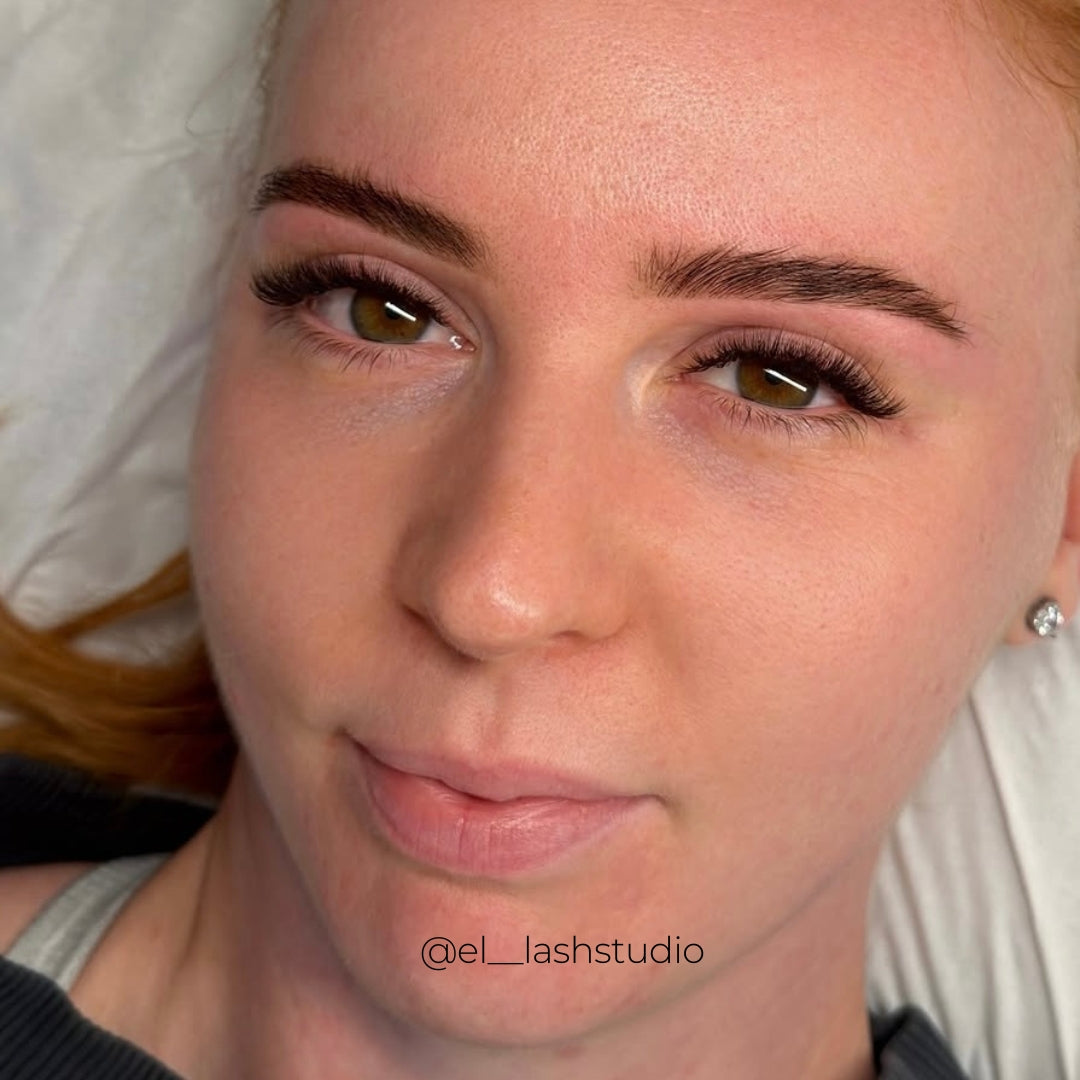 Close-up of soft, dark brown volume eyelash extensions with a fluffy, curled finish and subtly longer outer corners, framing hazel eyes.